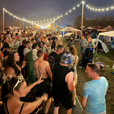Tanzende Festivalbesucher unter Lichterketten im Freien