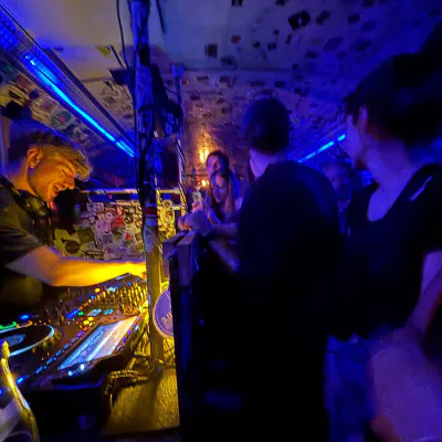 DJ am Mischpult in einem blau beleuchteten Club